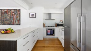 A modern kitchen with white cabinetry, a stainless steel refrigerator, and a wooden floor. - Cooinda, Red Hill South - Serene Red Hill South Retreat surrounded by gardens. (Red Hill South)