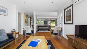 Una sala de estar moderna con una mesa de centro de madera, sofás de cuero negro y un televisor sobre un mueble de madera.