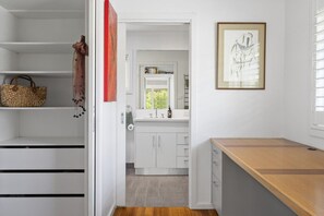 A modern bathroom with a white vanity, a wooden bench, and a framed artwork on the wall. - Cooinda, Red Hill South (Red Hill South)