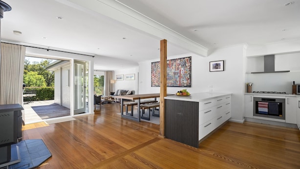 A modern kitchen with a dining area, wooden flooring, and a large window. - Cooinda, Red Hill South - Serene Red Hill South Retreat surrounded by gardens. (Red Hill South)