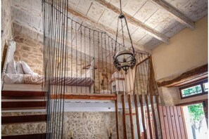 A rustic room with a stone wall, a wooden staircase, and a hanging light fixture.