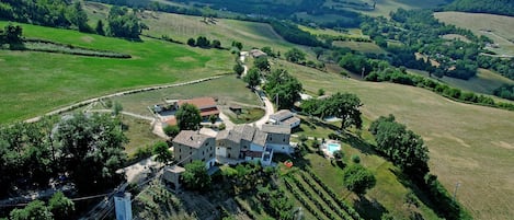 An aerial view of a rural property with a large house surrounded by fields and vineyards.