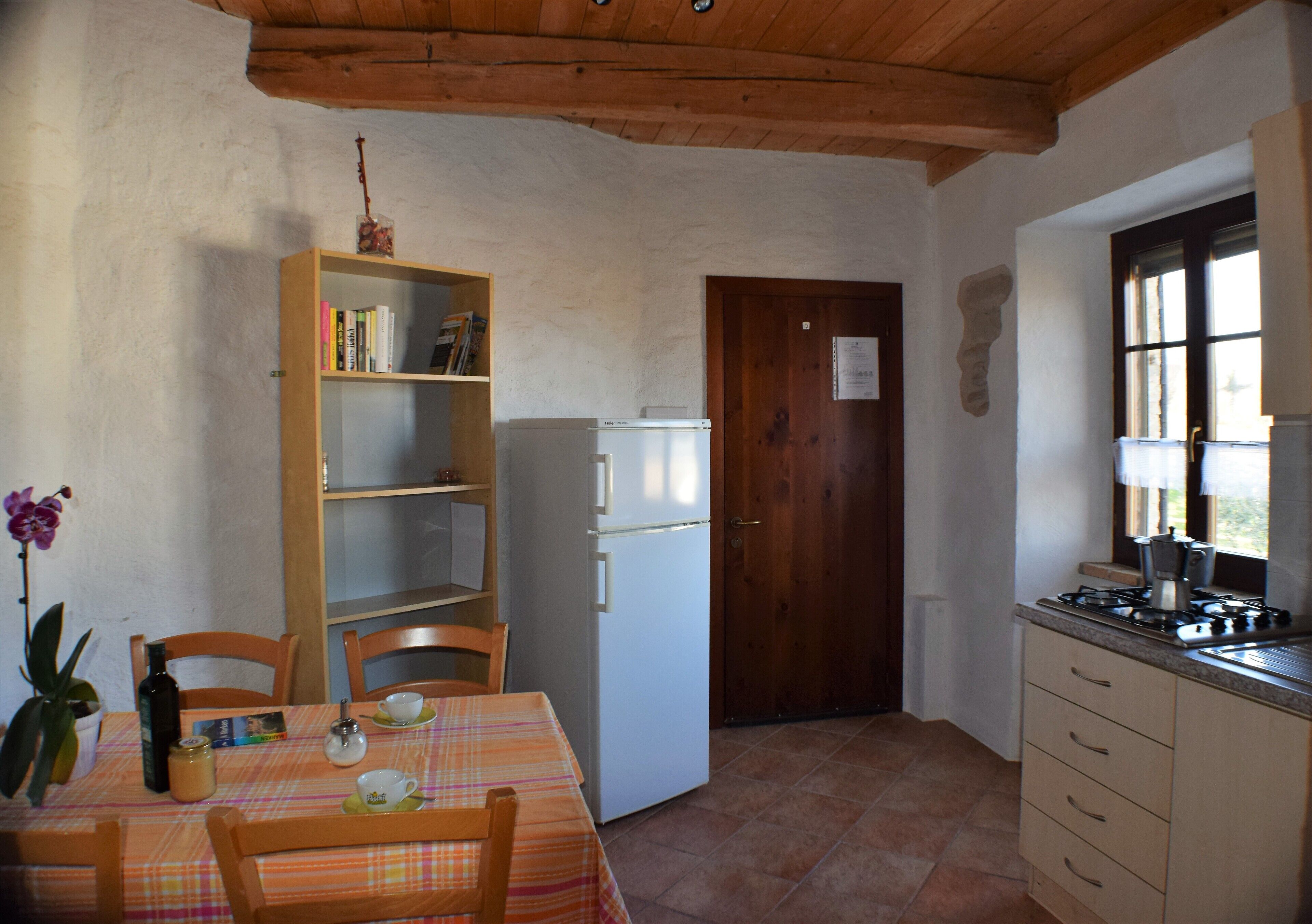 Une cuisine de taille réduite comprenant une table à manger, des chaises, un réfrigérateur et une fenêtre.