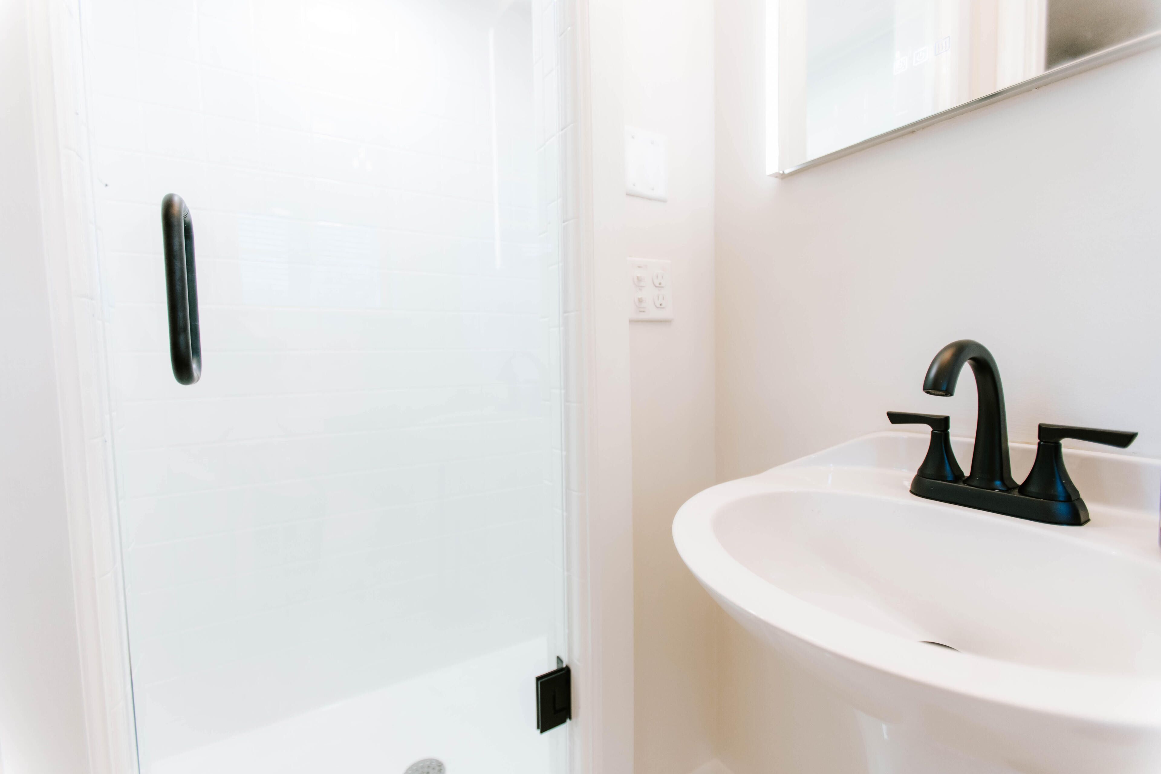 Une salle de bain avec un lavabo blanc et une porte de douche en verre.