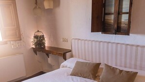 A neatly made bed with a brown quilt, white linens, and two pillows. A folded towel is on the bed. - CASA RURAL & SPA LA GRAJA (Chinchón)
