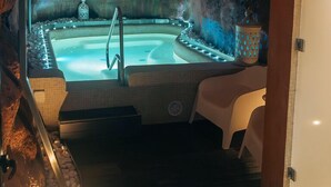 A spa area with a hot tub, seating, and a decorative lantern. - CASA RURAL & SPA LA GRAJA (Chinchón)