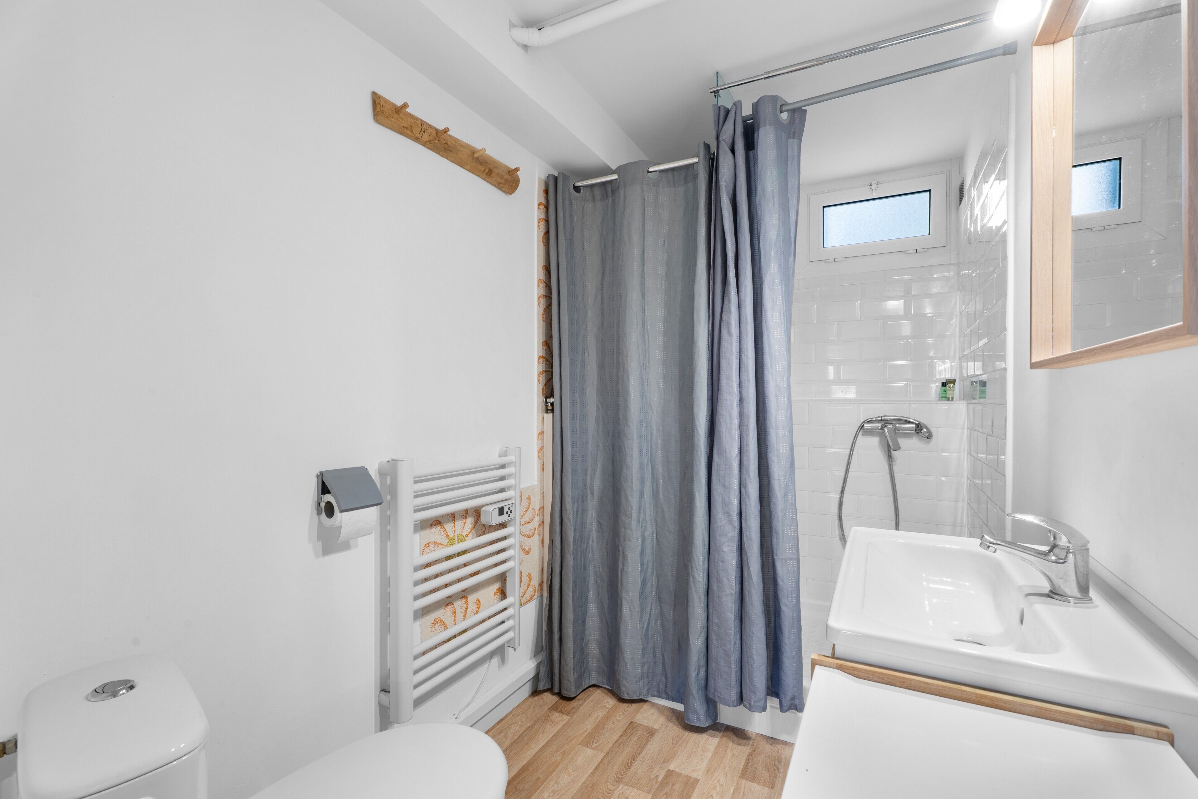 A bathroom with a toilet, a shower with a curtain, a sink, and a mirror.