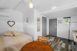 Ein Schlafzimmer mit Bett, einem Holzbstuhl, einem Tisch, einer herzförmigen Dekoration und einem Spiegel.