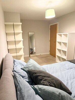 Ein Schlafzimmer mit einem Bett, einem Kleiderschrank, einem Spiegel und einer Hängelampe.