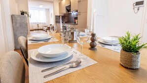 Un coin repas avec une table en bois mise pour quatre personnes, comprenant des assiettes, des couverts et des verres à vin.