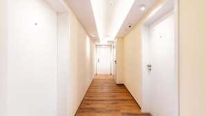 Un long couloir étroit, doté d’un plancher en bois et de murs blancs, qui mène à une porte au fond.