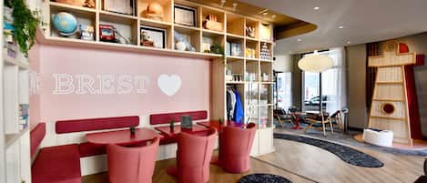 A modern interior with a red and white color scheme, featuring a seating area with red chairs and a bench, a bookshelf with various items, and a wall with the word "BREST" and a heart symbol.