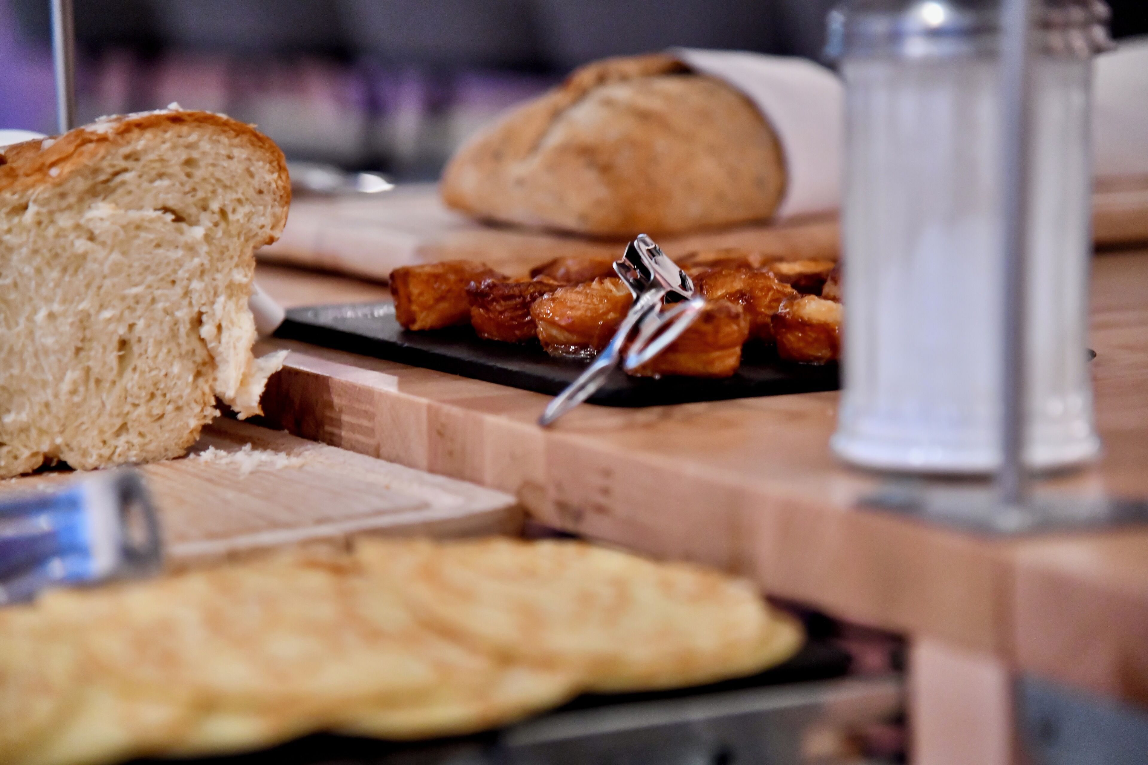 Ein Frühstückstisch mit Brot, Gebäck und einem Salzstreuer.
