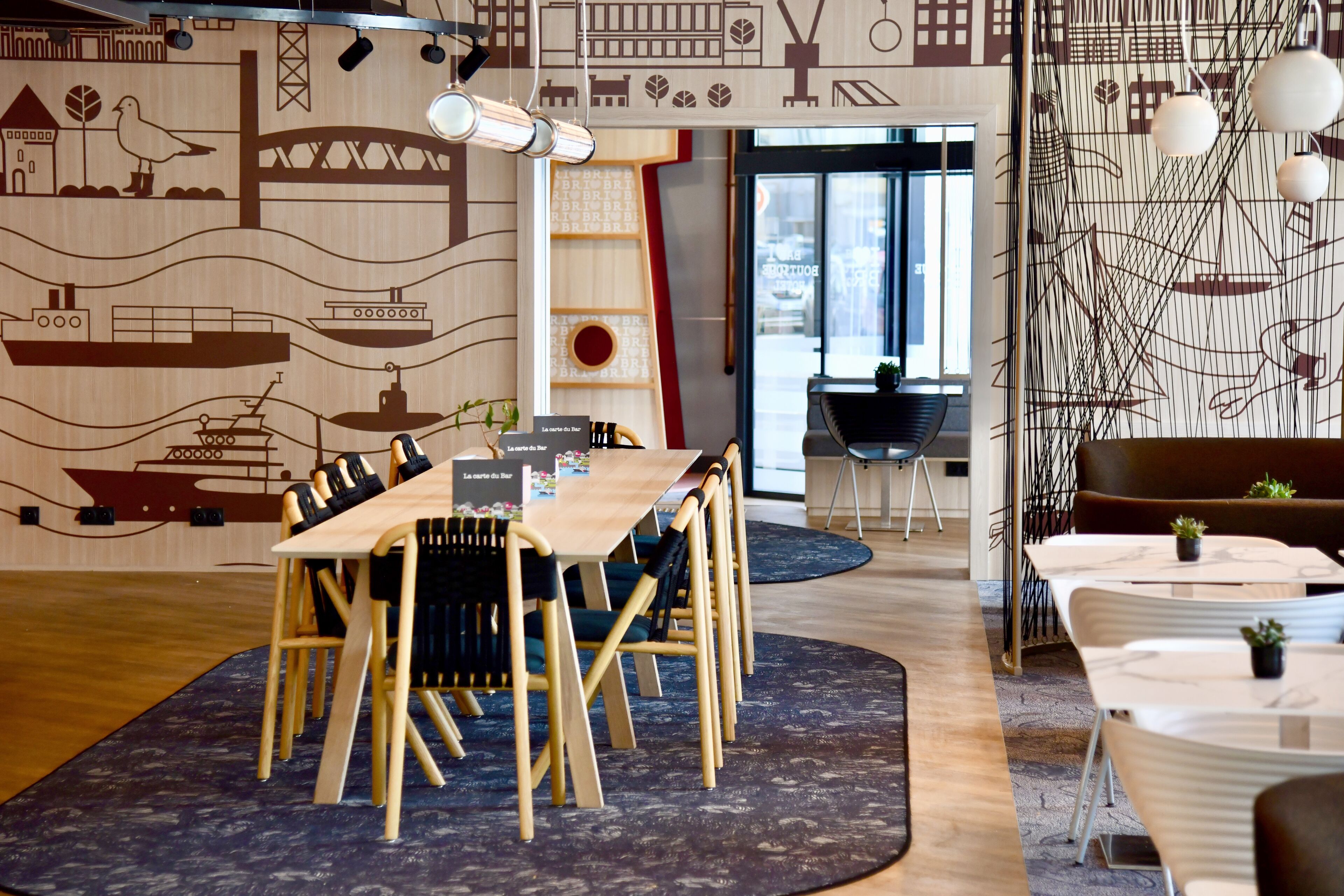 Un moderno comedor con una mesa y sillas de madera, un mural de pared estampado y vistas de la ciudad a través de amplias ventanas.