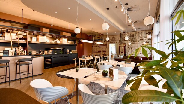 A modern restaurant with a bar area, seating arrangements, and hanging pendant lights. - ibis Budget Brest Centre Port (Brest)