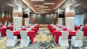 A conference room with rows of tables, white chairs, and a patterned carpet. - Mercure Jakarta Grogol (Jakarta)