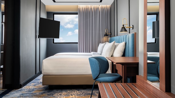 A modern hotel room with a bed, a desk, a chair, a TV, and a window with curtains. - Mercure Jakarta Grogol (Jakarta)