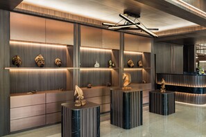 Un interior moderno con paneles de madera, iluminación empotrada y objetos decorativos en estantes y pedestales.