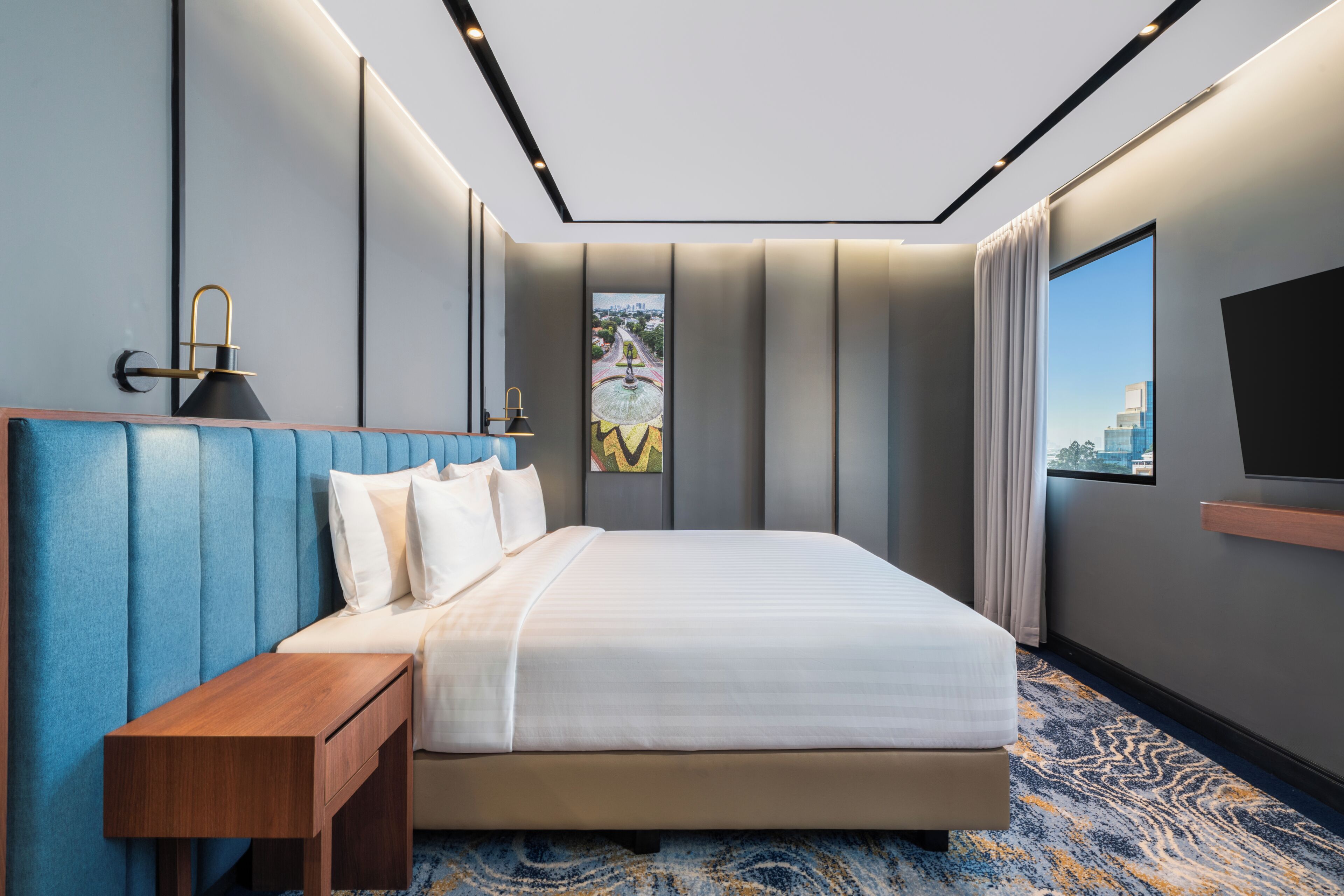 Habitación de hotel moderna con una cama grande, una mesita de noche de madera, un televisor de pantalla plana y vistas a la ciudad.
