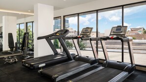 A gym with treadmills, exercise equipment, and large windows offering a view of the city. - Mercure Jakarta Grogol (Jakarta)