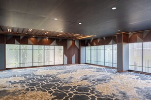 Um quarto espaçoso com carpete estampado, painéis de madeira nas paredes e teto com iluminação embutida.