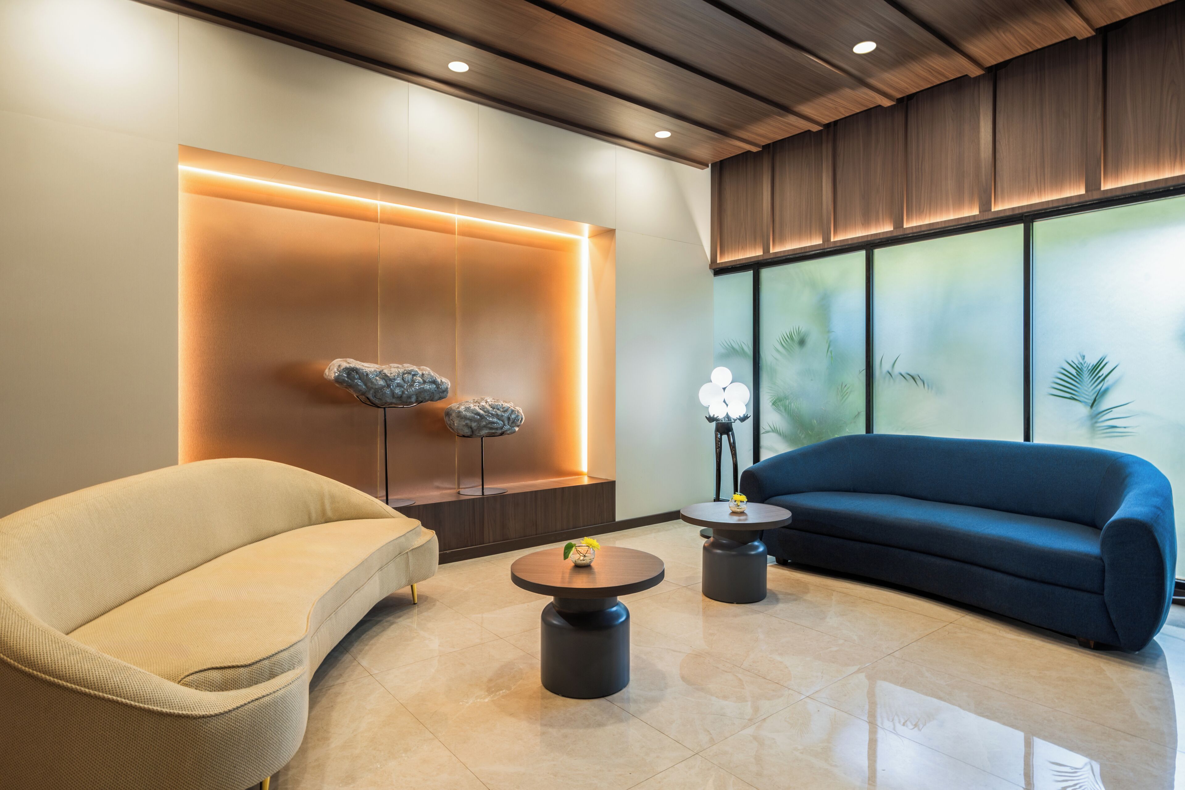 Un área de descanso moderna con sofá, sillón y una escultura de roca singular.