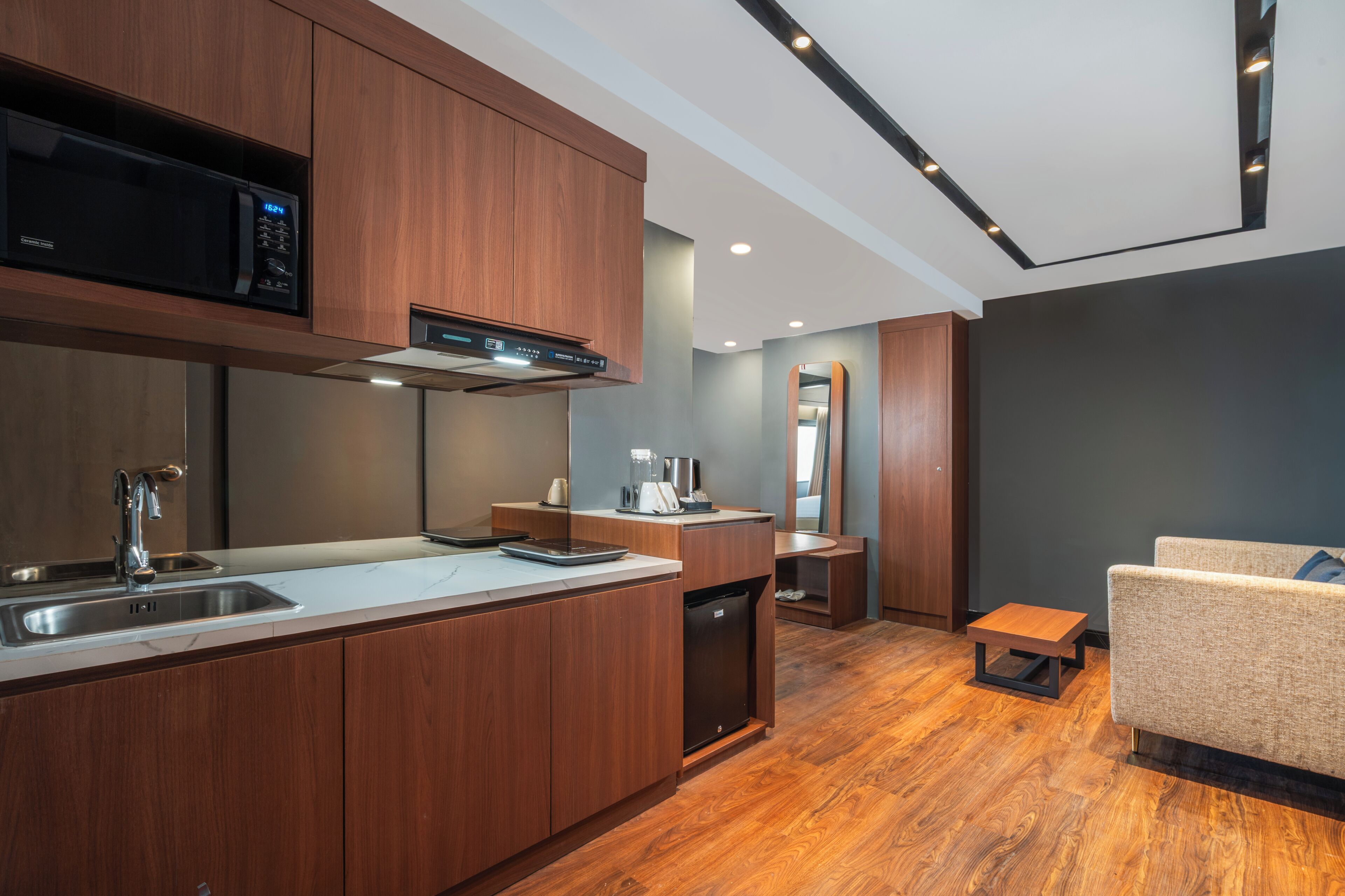 A modern kitchen with a built-in microwave, stainless steel sink, and wooden cabinets.