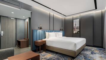 A modern hotel room with a large bed, bedside tables, a desk, and a view of a cityscape.