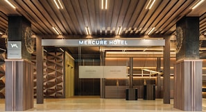 The entrance to the Mercure Hotel with a modern design, featuring a prominent sign, a reception desk, and a geometric wall pattern. - Mercure Jakarta Grogol (Jakarta)