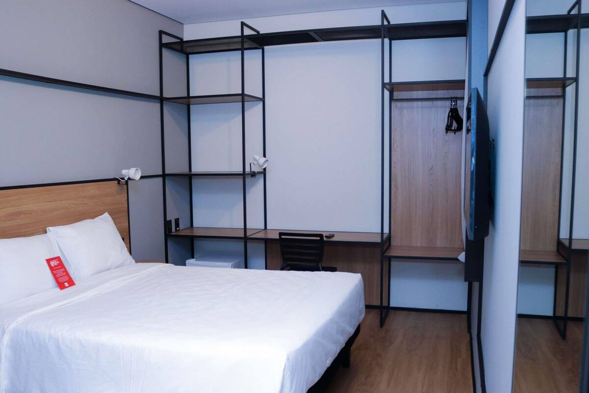 A hotel room with a bed, a desk, and a wardrobe.