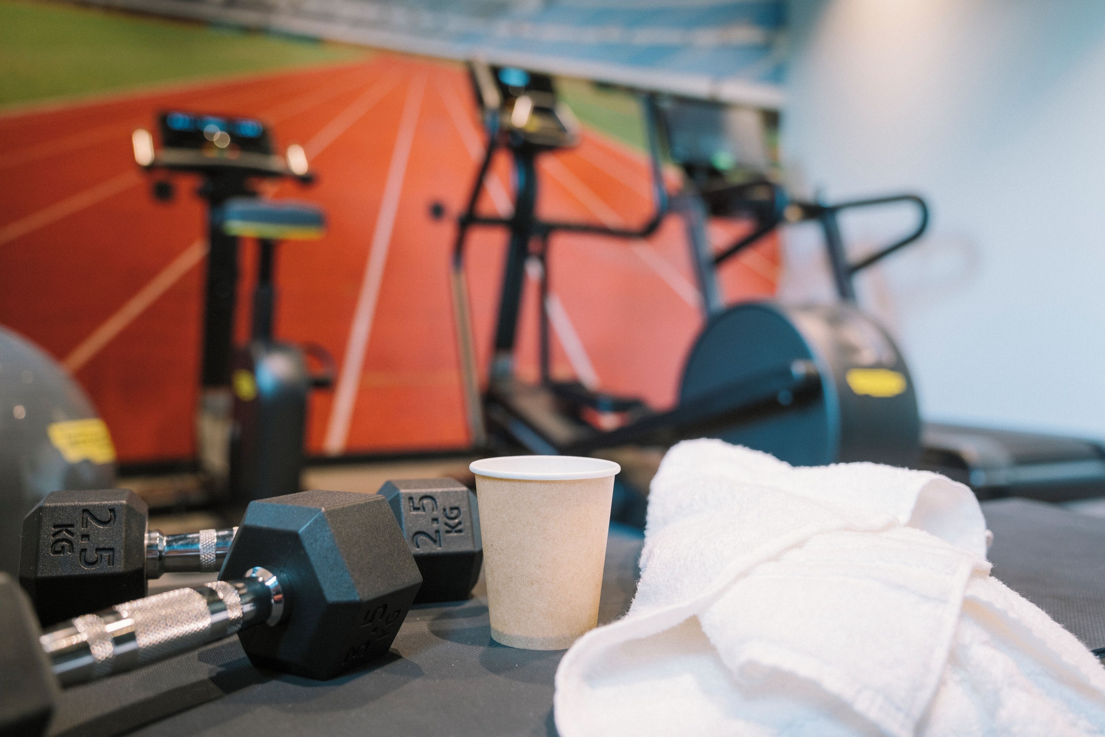 A gym with exercise equipment, a towel, and a water bottle.