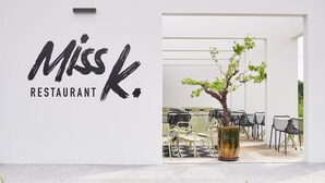 A restaurant sign with a modern design and a seating area with chairs and a potted tree. - Mercure Quimper Kerlic (Quimper)