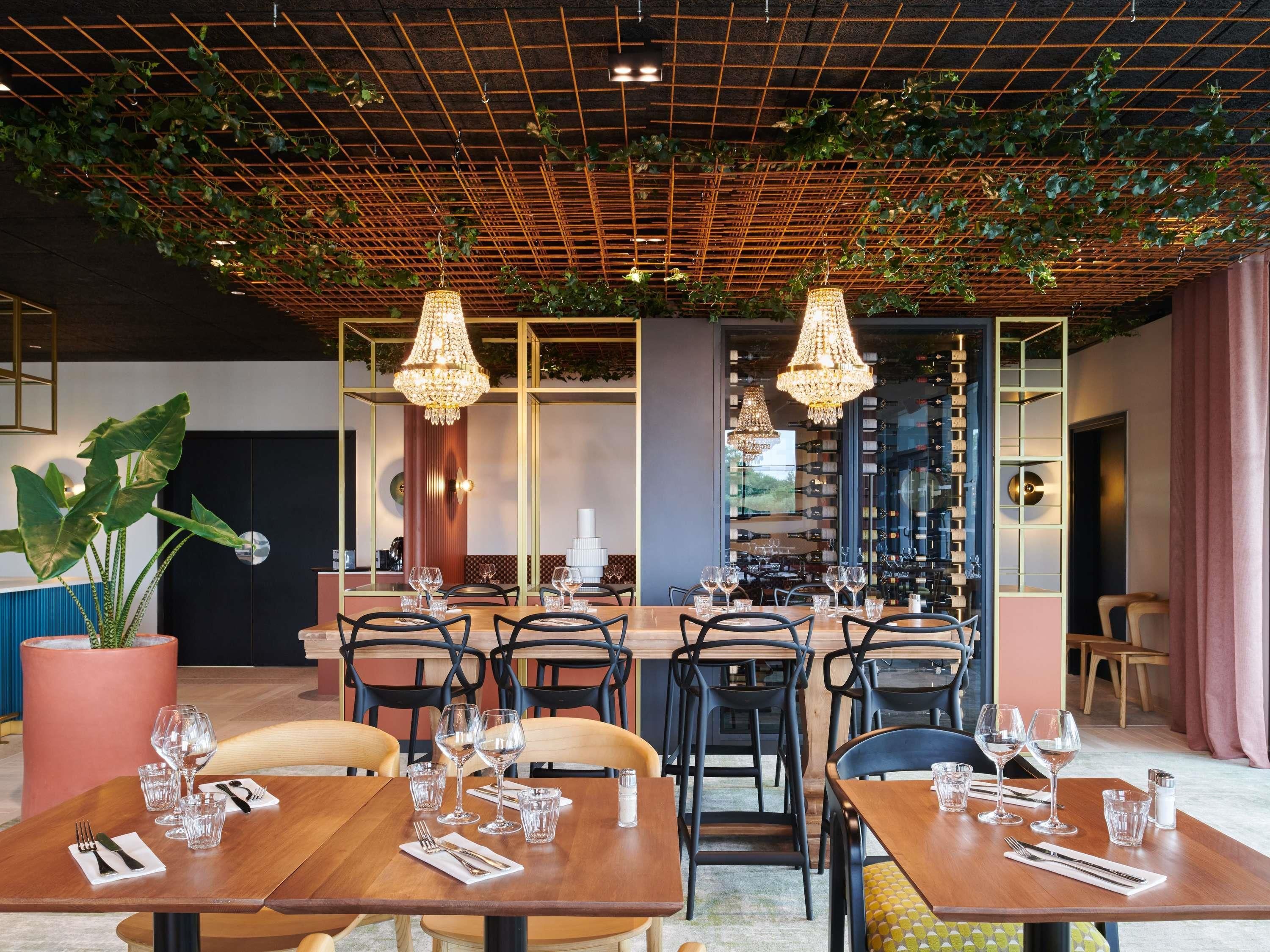 Ein Restaurant mit Rasterdecke, hängenden Kronleuchtern und einem Weinkühlschrank.