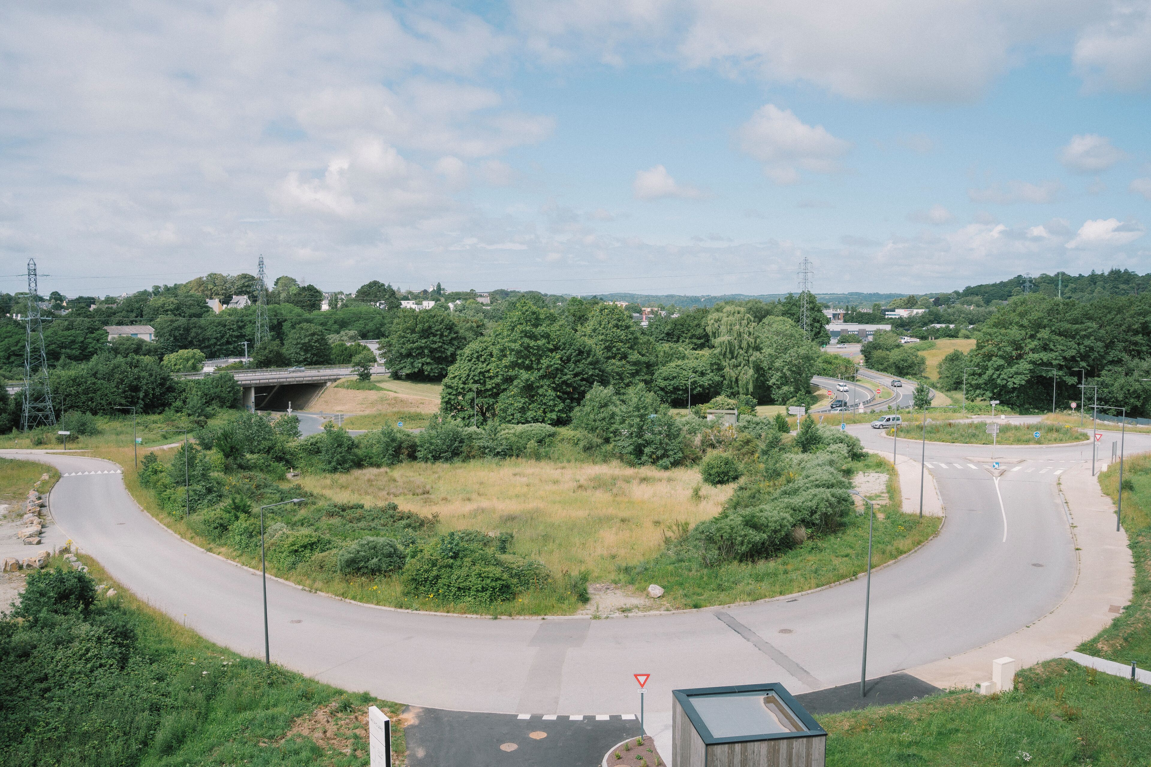 A roundabout with greenery, a bridge, and a road.