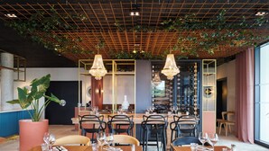 A restaurant with wooden tables, chairs, hanging plants, and chandeliers. - Mercure Quimper Kerlic (Quimper)