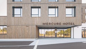 A modern building with a wooden facade and multiple windows. The name 'Mercure Hotel' is visible above the entrance. - Mercure Quimper Kerlic (Quimper)
