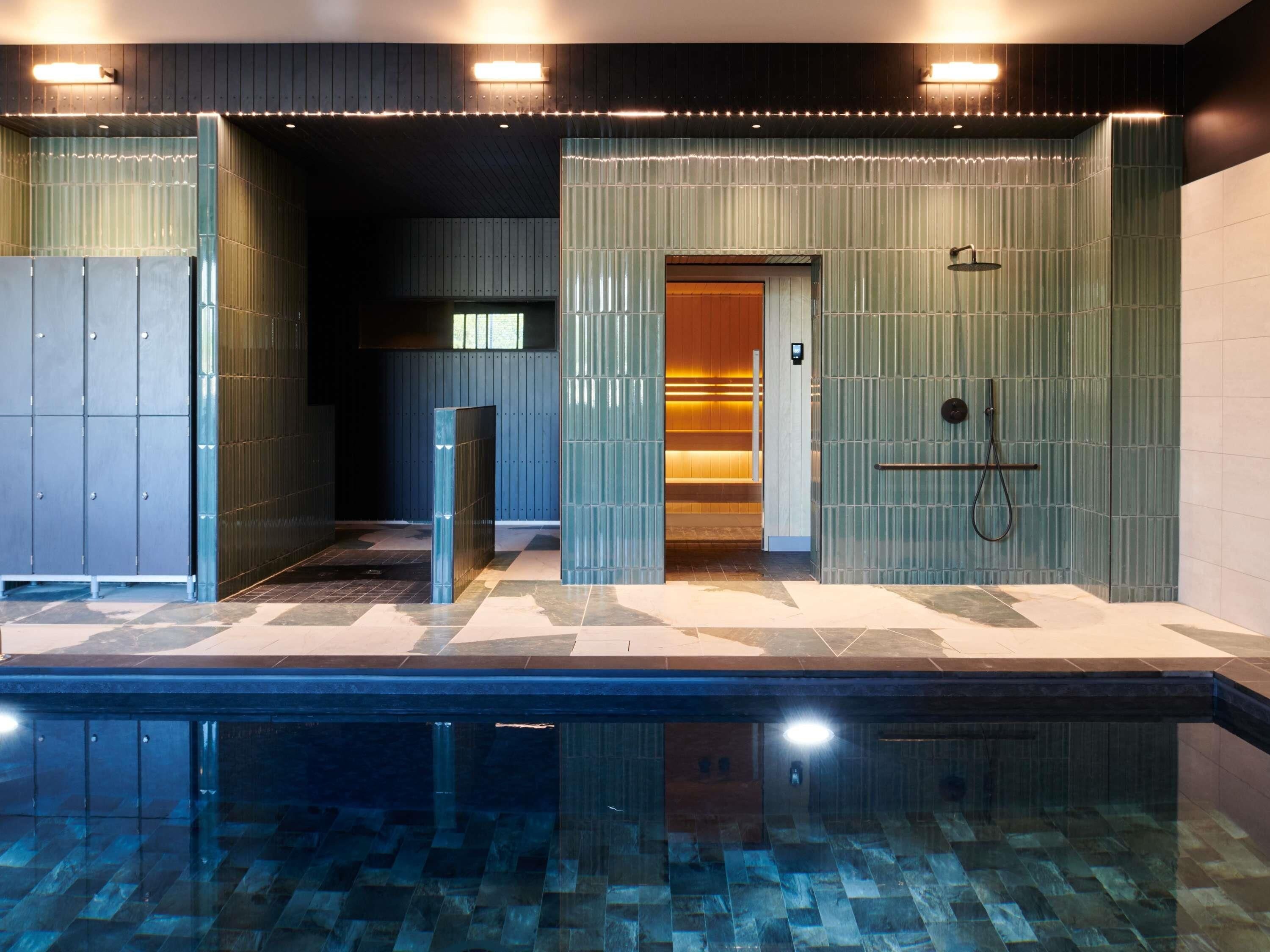 A modern bathroom with a glass-enclosed shower, a tiled floor, and a visible towel rack.