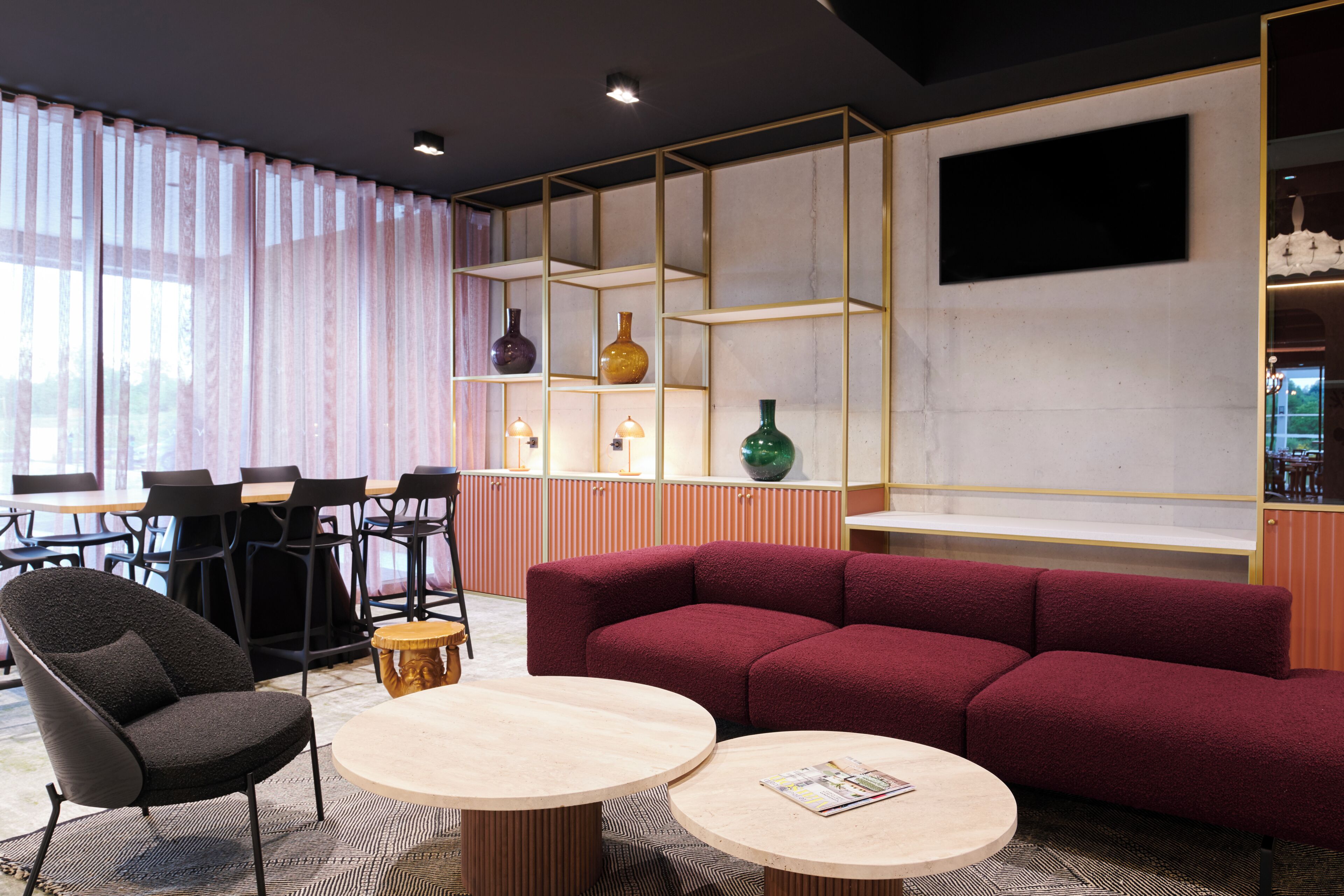 Een modern interieur met een rode bank, een ronde tafel, een zwarte stoel, en een eetgedeelte met stoelen en een tafel.