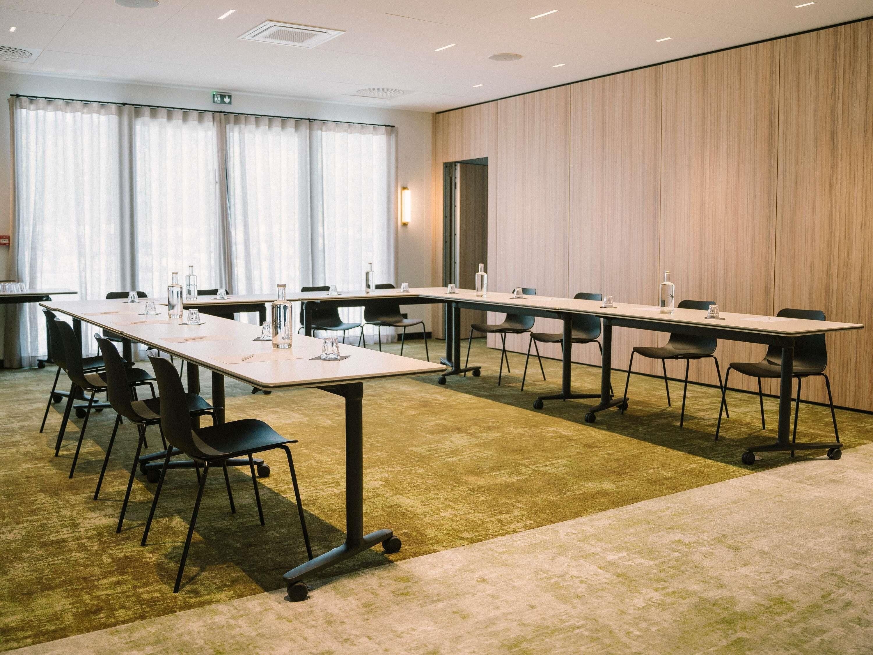 A conference room with a long table, chairs, and a carpeted floor.