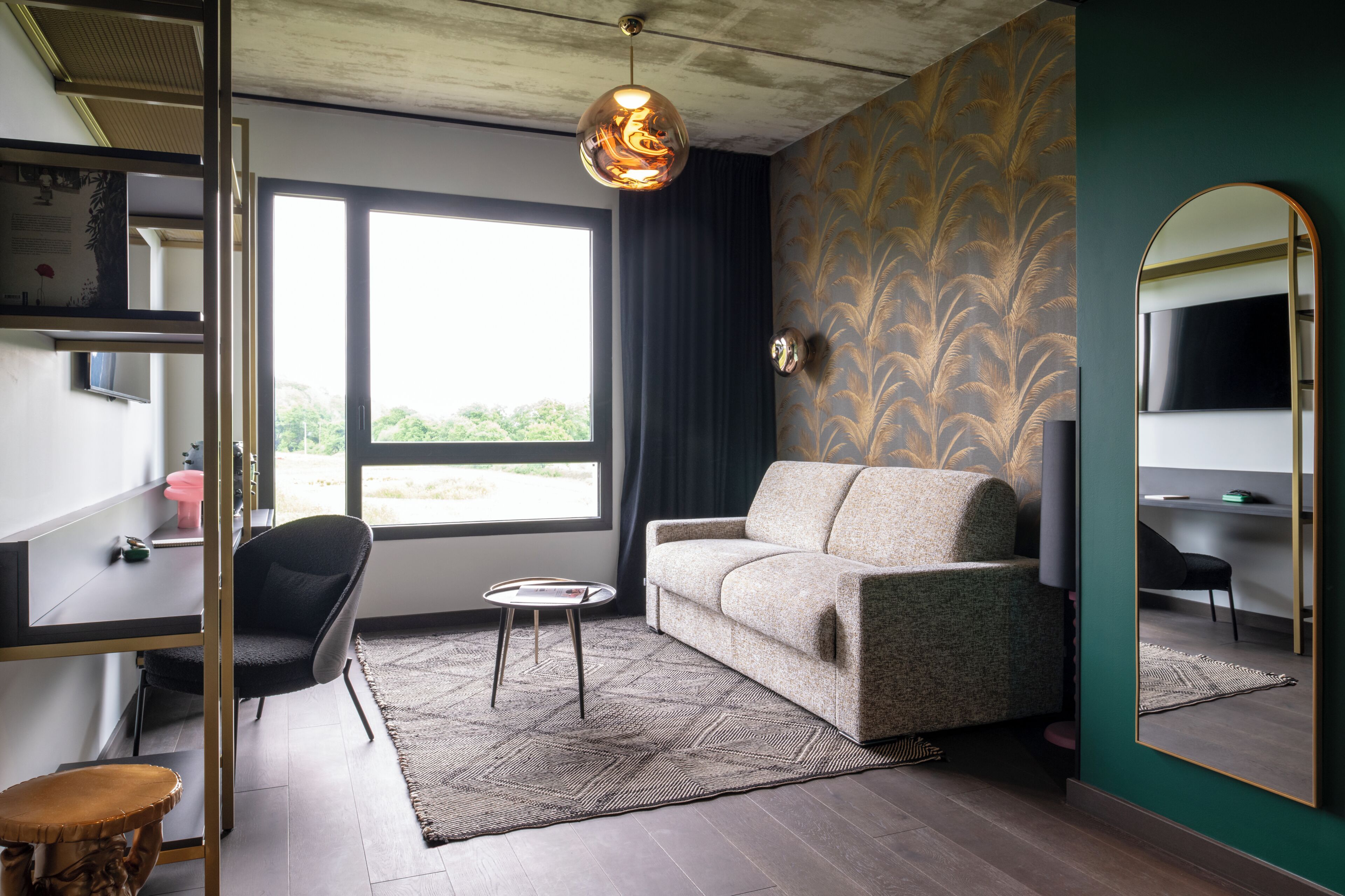 Ein modernes Wohnzimmer mit einer Couch, einem kleinen Tisch, einem Sessel, einem großen Fenster und einem Spiegel.