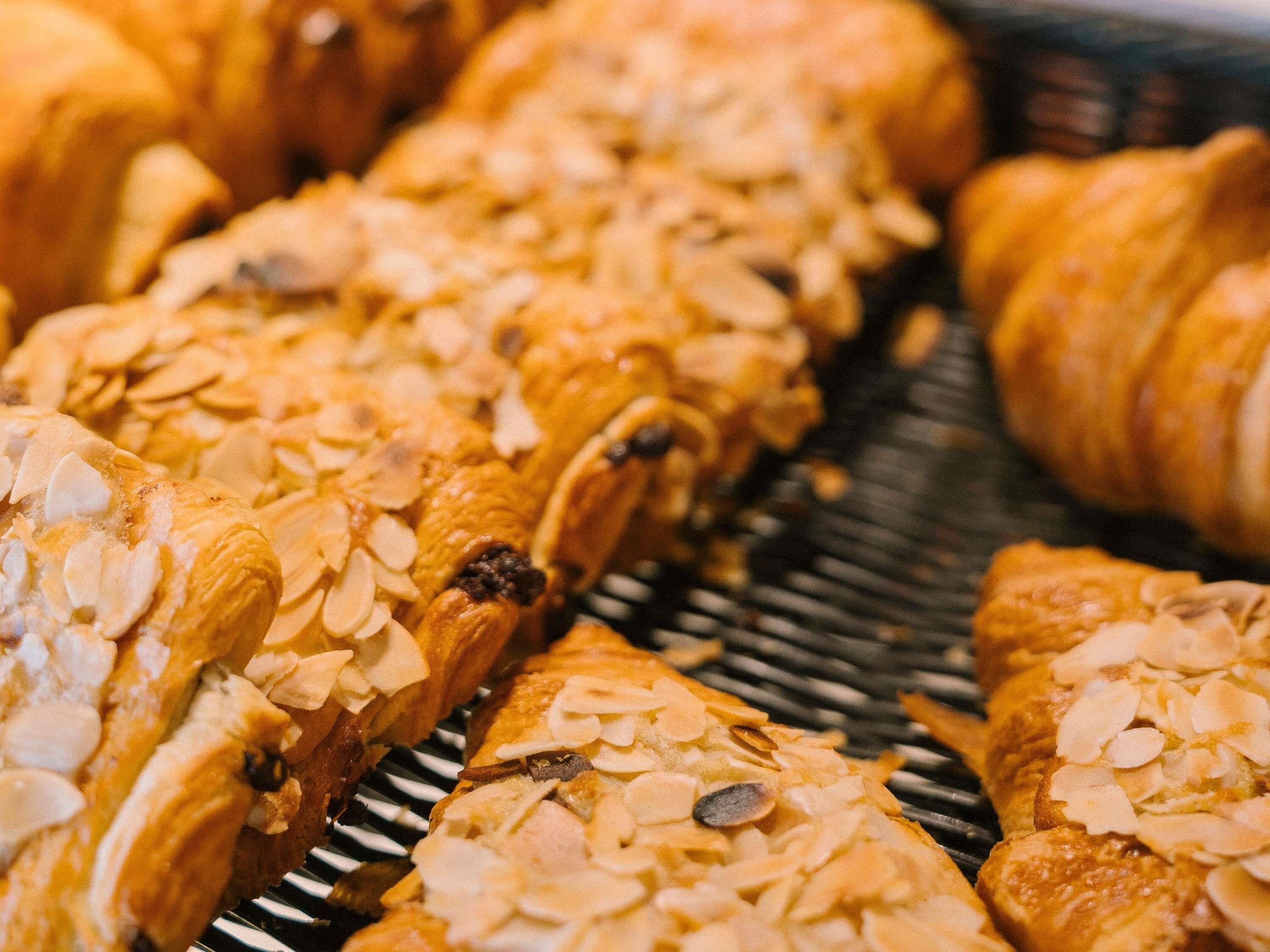 Eine Auswahl an Gebäck, darunter Croissants und Gebäck mit Mandelbelag, präsentiert auf einem Korb.