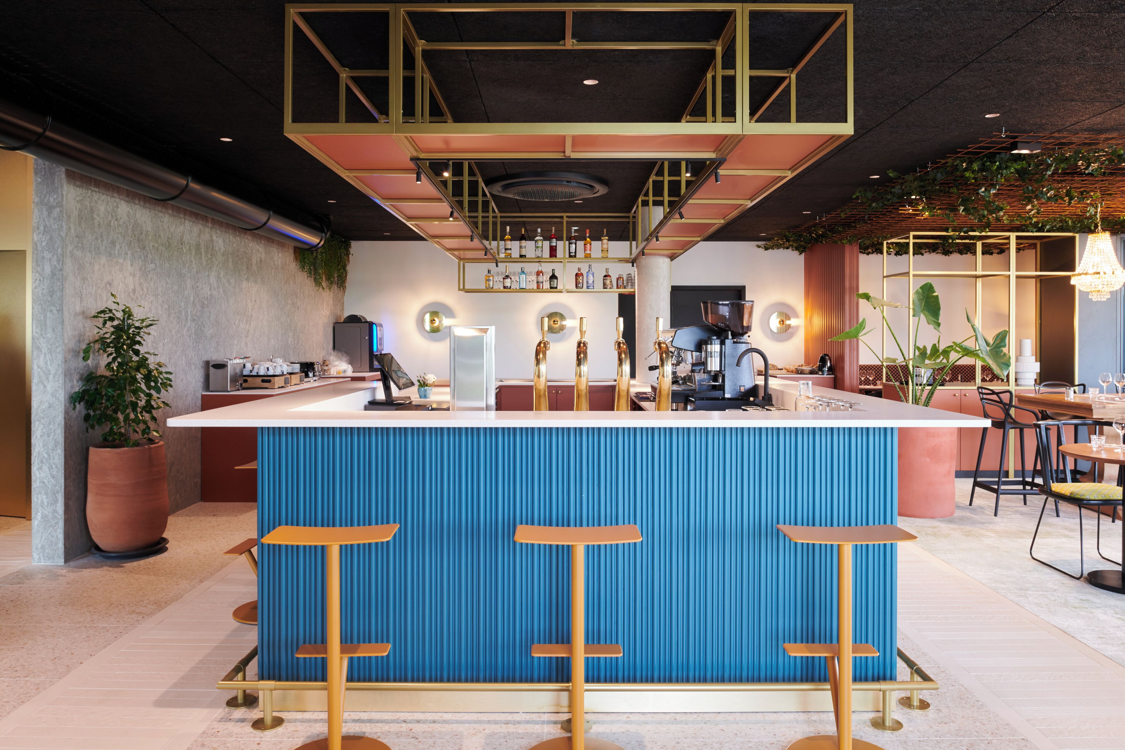 A modern bar area with a blue bar counter, stools, and a variety of bottles.