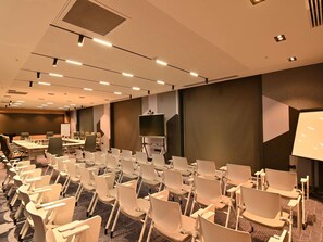A conference room with rows of chairs, a large screen, and a whiteboard. - Mercure Tashkent North (Tashkent)