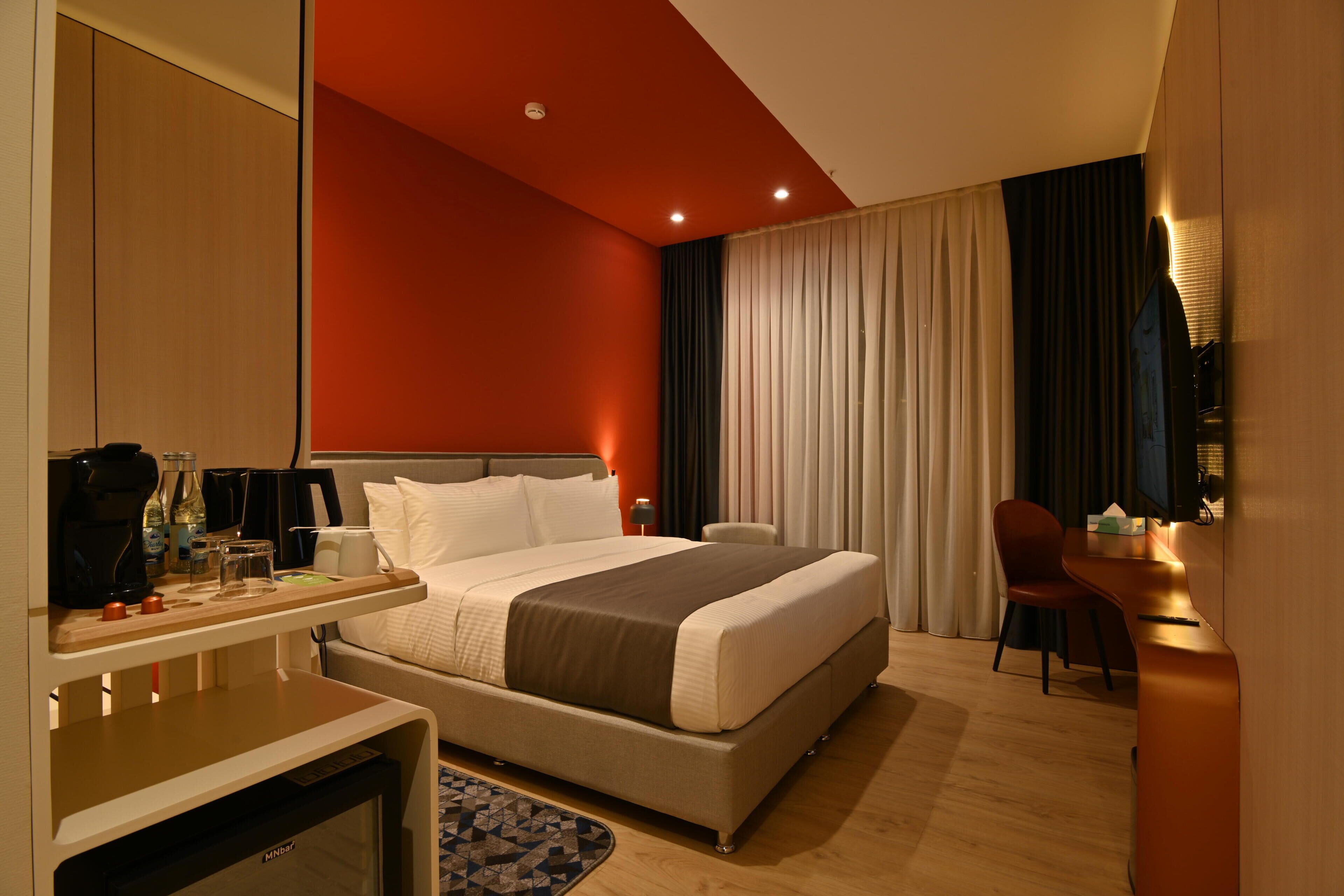 Ein Hotelzimmer mit Bett, Schreibtisch, Stuhl und einer Minibar.