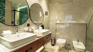 Ein modernes Badezimmer mit zwei Waschbecken, einem Bidet, einer Toilette und einem großen Spiegel.
