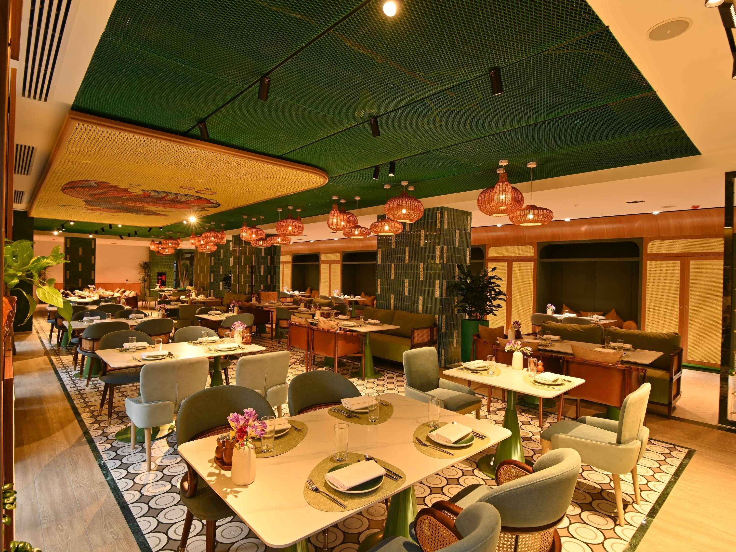 A restaurant with multiple dining tables, chairs, and hanging light fixtures.