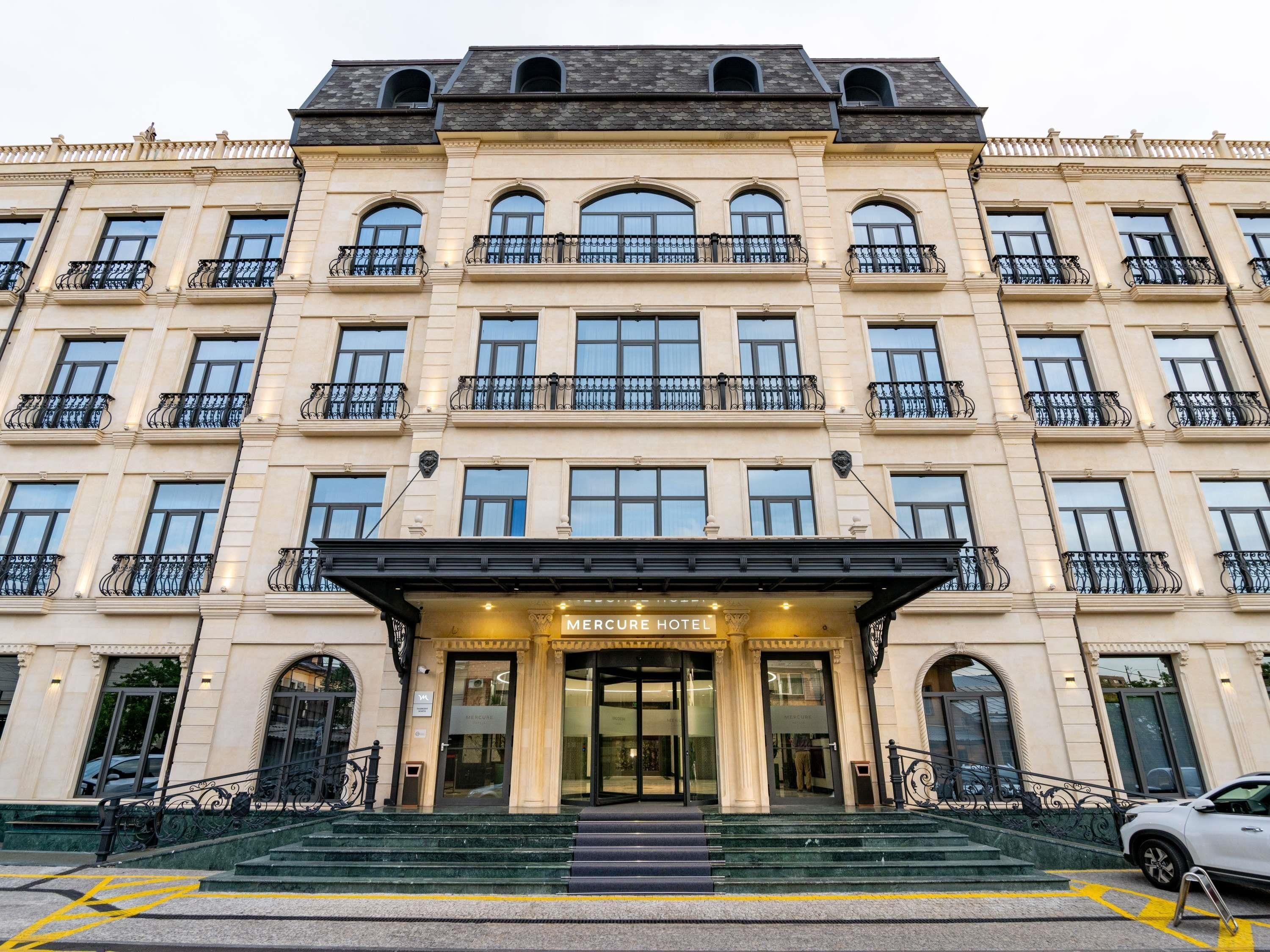A multi-story hotel with a classic architectural style, featuring a grand entrance with steps leading up to the main doors.