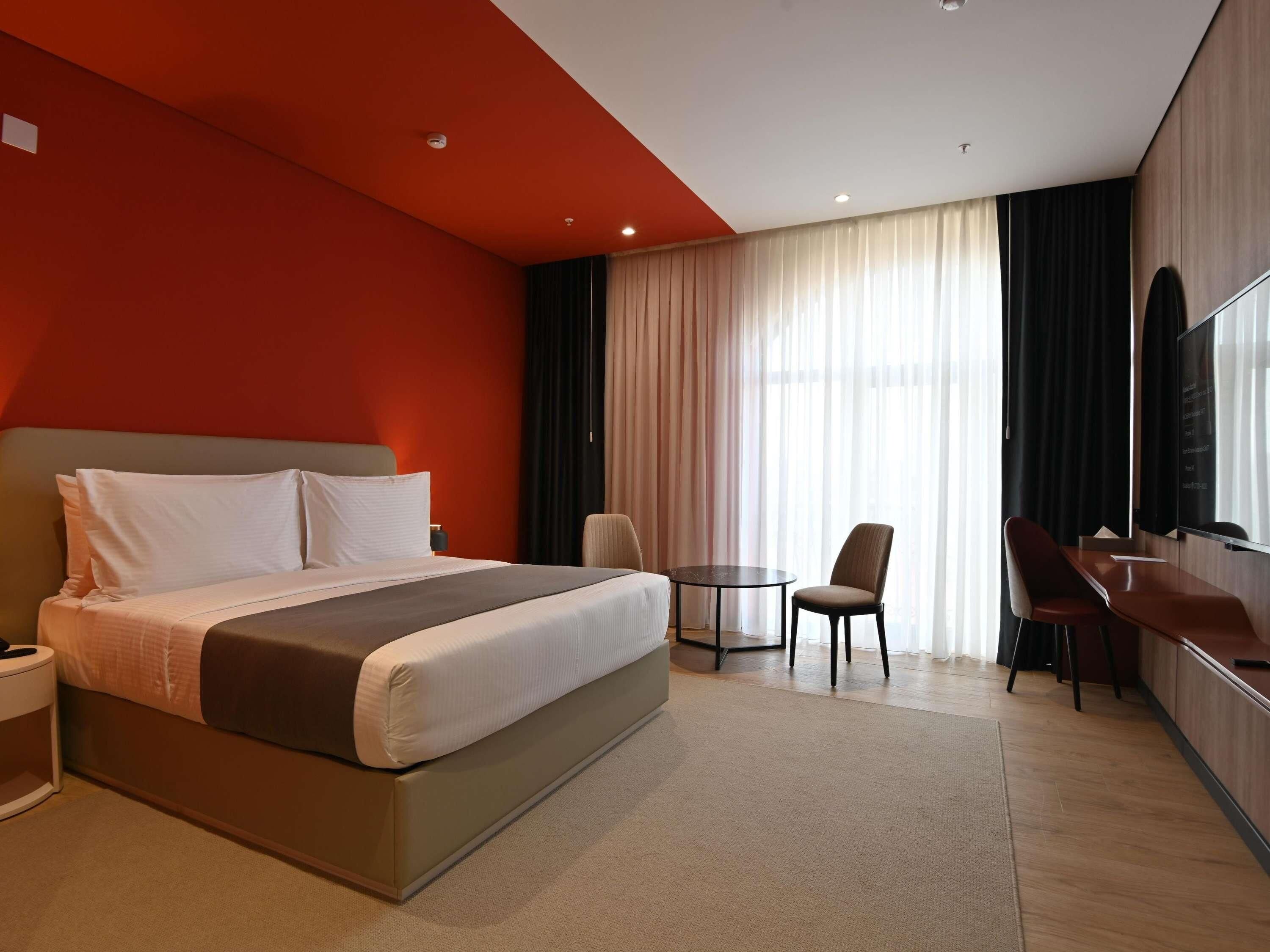 A modern hotel room with a large bed, a desk, and a chair.