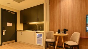 A compact kitchen with a refrigerator, a sink, and a dining area with two chairs and a small table. - Mercure Tashkent North (Tashkent)