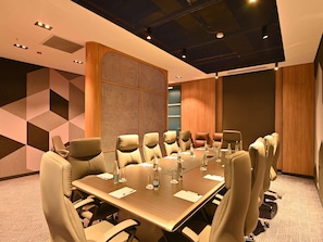 A conference room with a long table, multiple chairs, and a decorative wall. - Mercure Tashkent North (Tashkent)